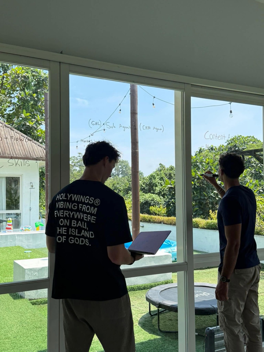 Liam and Victor working beside a window covered in handwritten workflow notes.